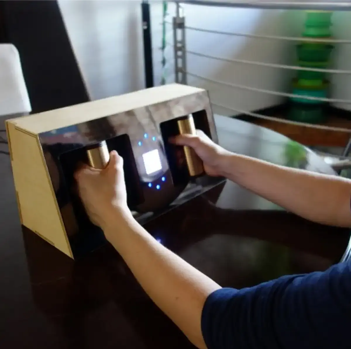Deux bras tenant une boîte rectangulaire équipée de poignées et d'un écran tactile