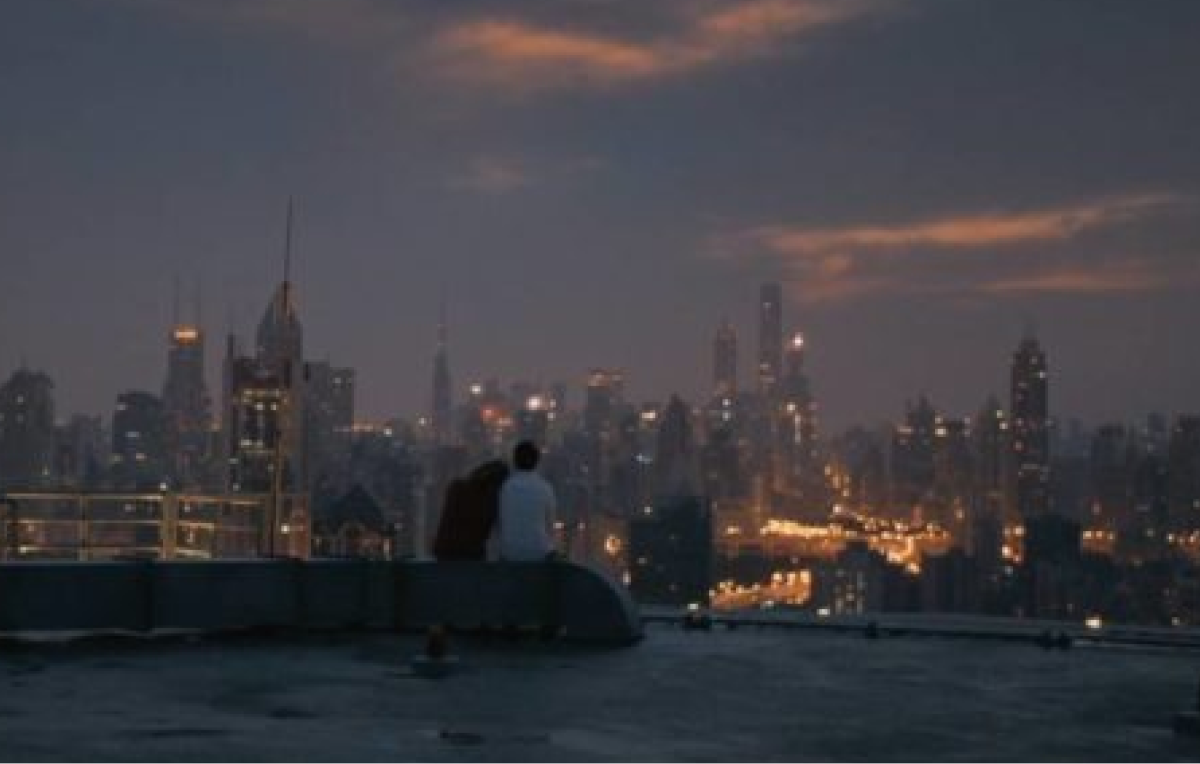 Théodore et Amy assis sur un toit avec la ville éclairée au loin