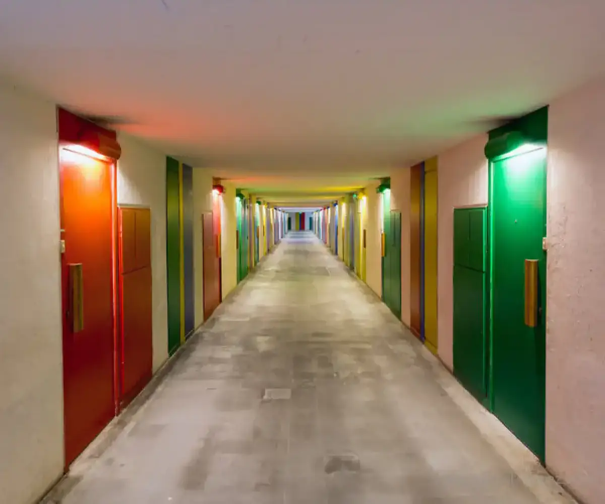 Long couloir bordé de portes rouges, vertes, jaunes et bleues