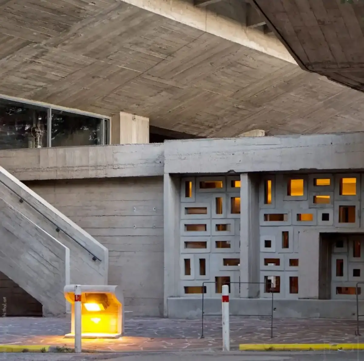 Structure en béton avec des petites ouvertures en mosaïque donnant sur un trottoir
