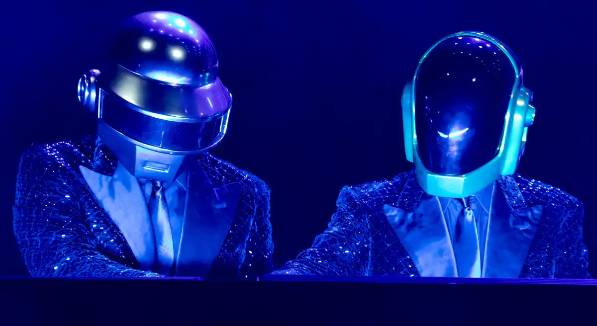 Les Daft Punk en costard cravate scintillants sous une lumière bleue